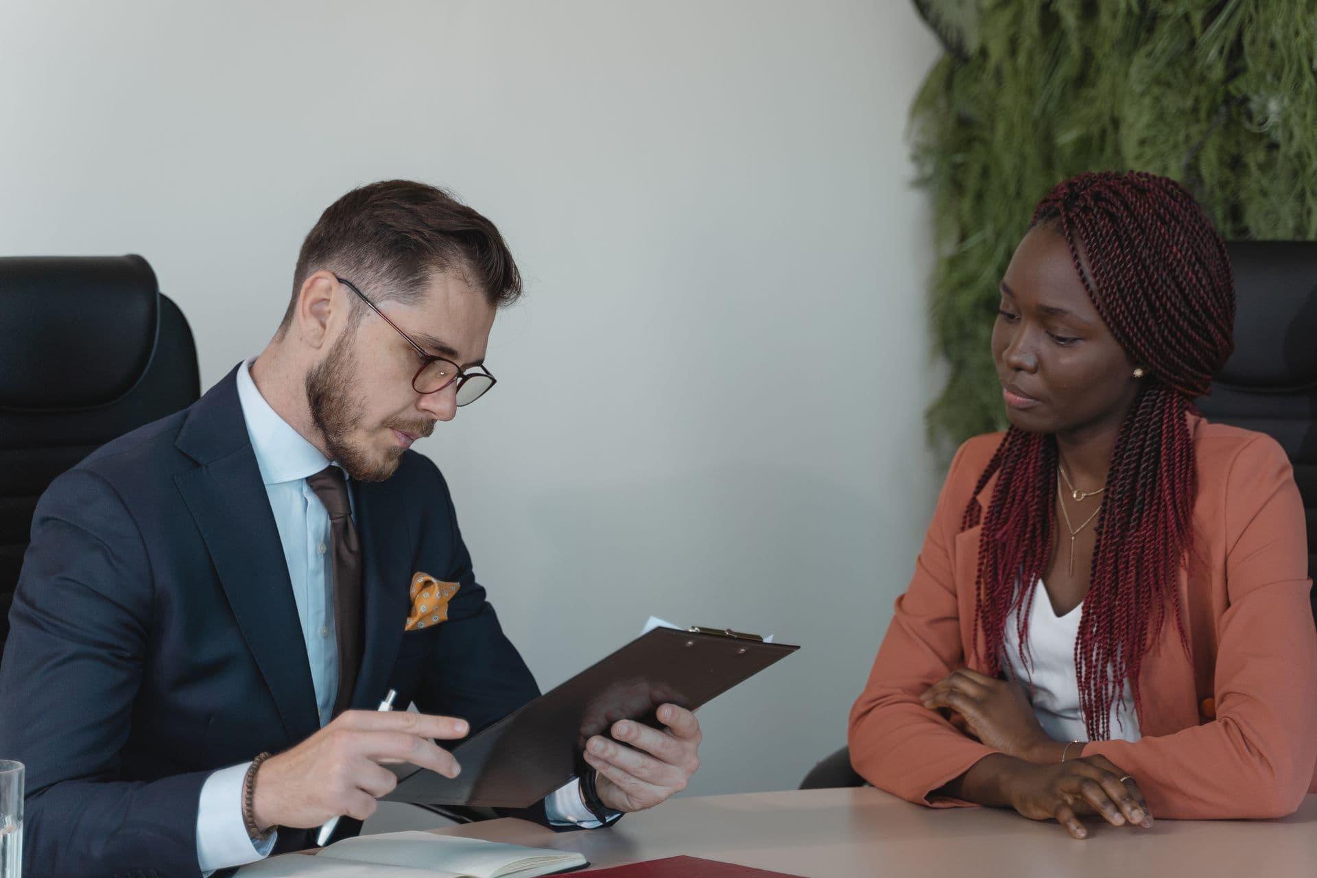 Two teammates review paperwork together across an office desk