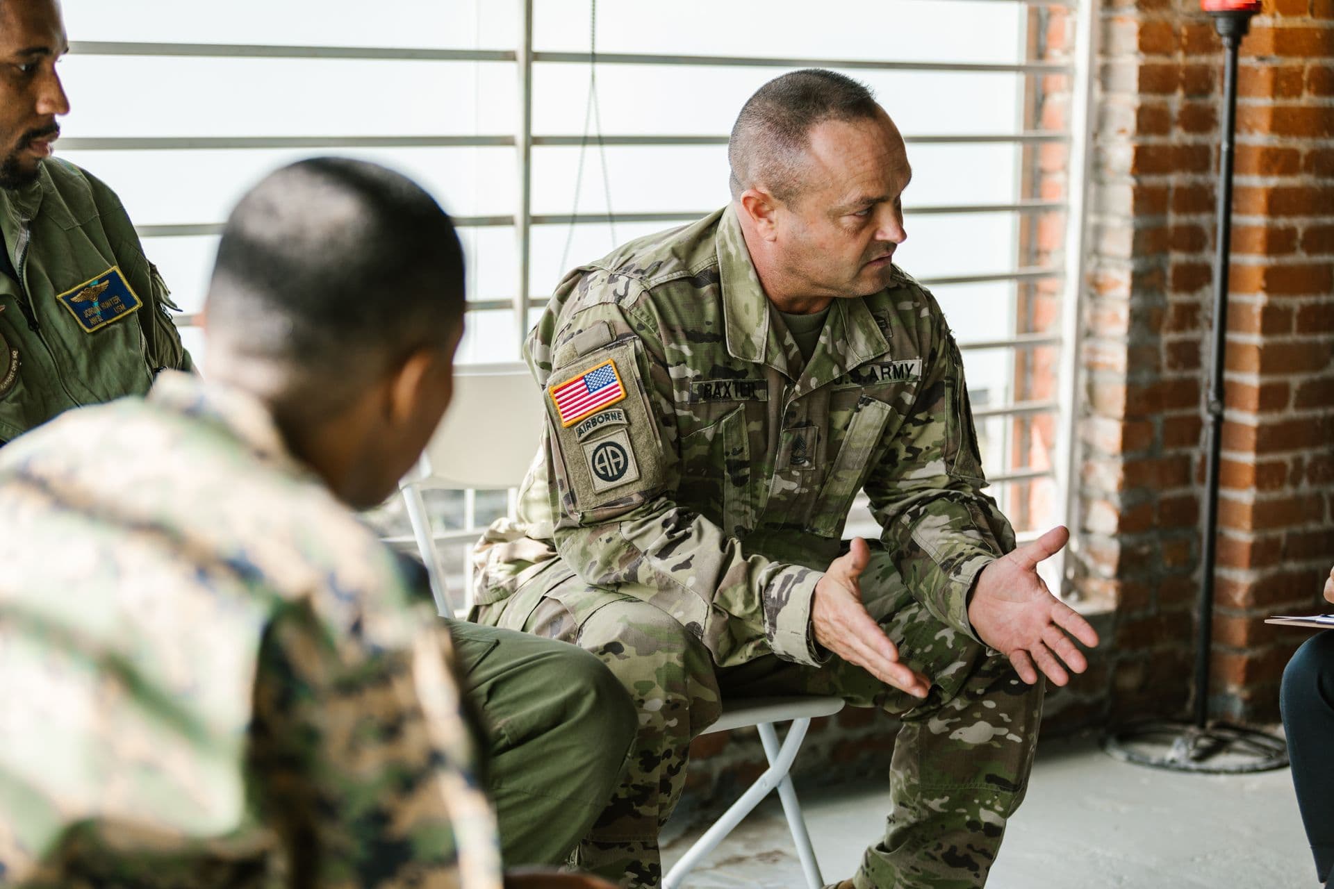 A senior soldier talks through next steps with a small group, gesturing as he explains